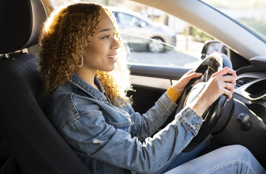 Car Locksmith Near Me Ottawa Curly haired woman driving a car happy at sunset.